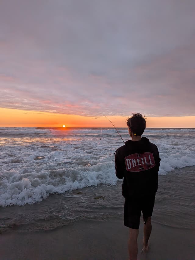 Matthew fishing at sunset on the beach